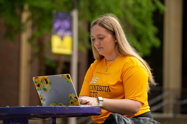Student sitting outside at a table working on her computer. 