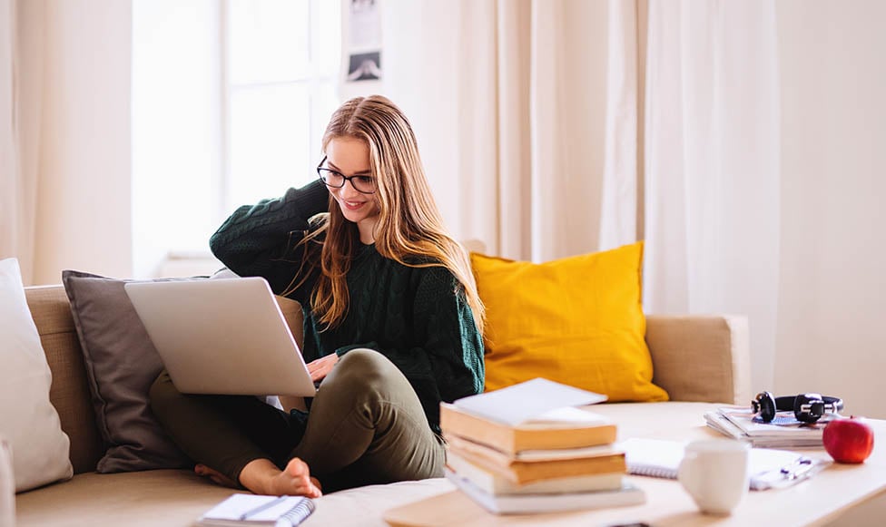 Student sitting on couch working on laptop