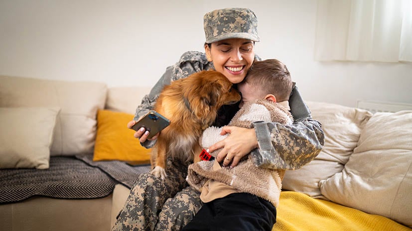 a person in military uniform holding a dog and a child
