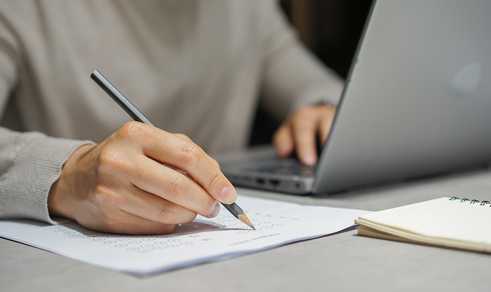 a person writing on a piece of paper with a pencil