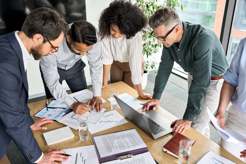 Group standing over a table talking about plans. 