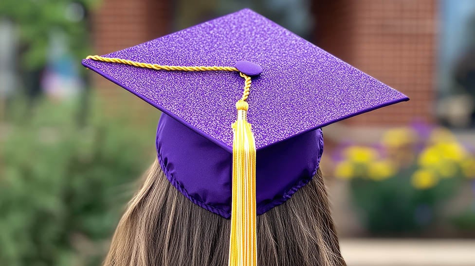 female graduate with her purple cap and gown on facing away from the camera