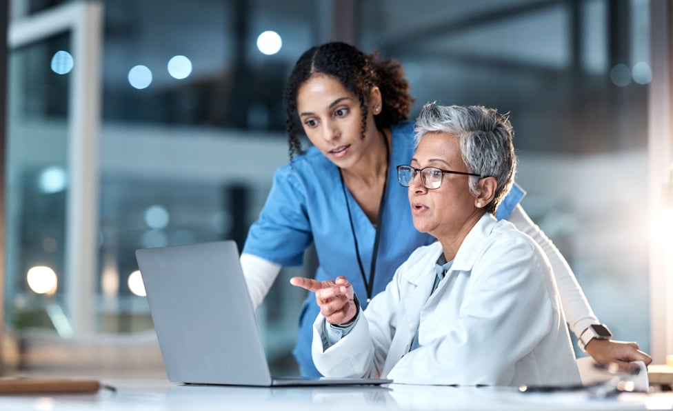 Doctor and nurse looking at a computer having a discussion. 