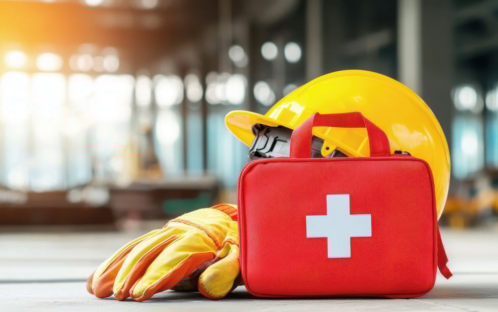 Medical bag sitting on the ground with a yellow helmet and glove.
