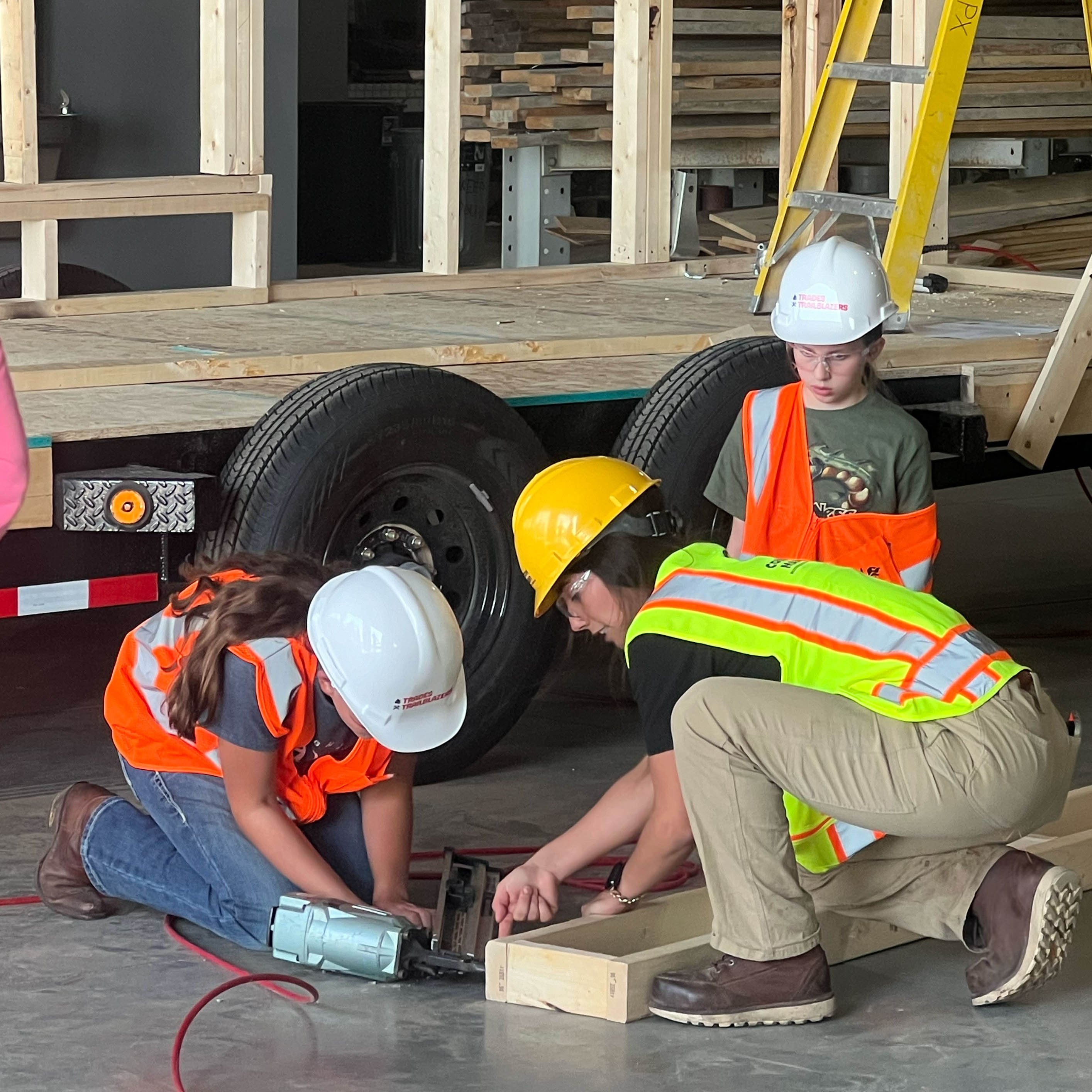 Malia Riordan and a young construction worker. Working on a shop floor as nail into a wooden box. 
