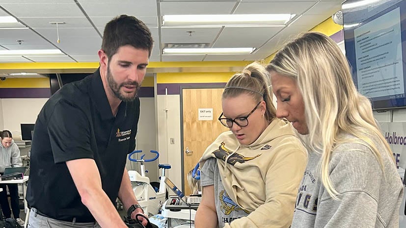 Professor working with two students in a lab with research equipment