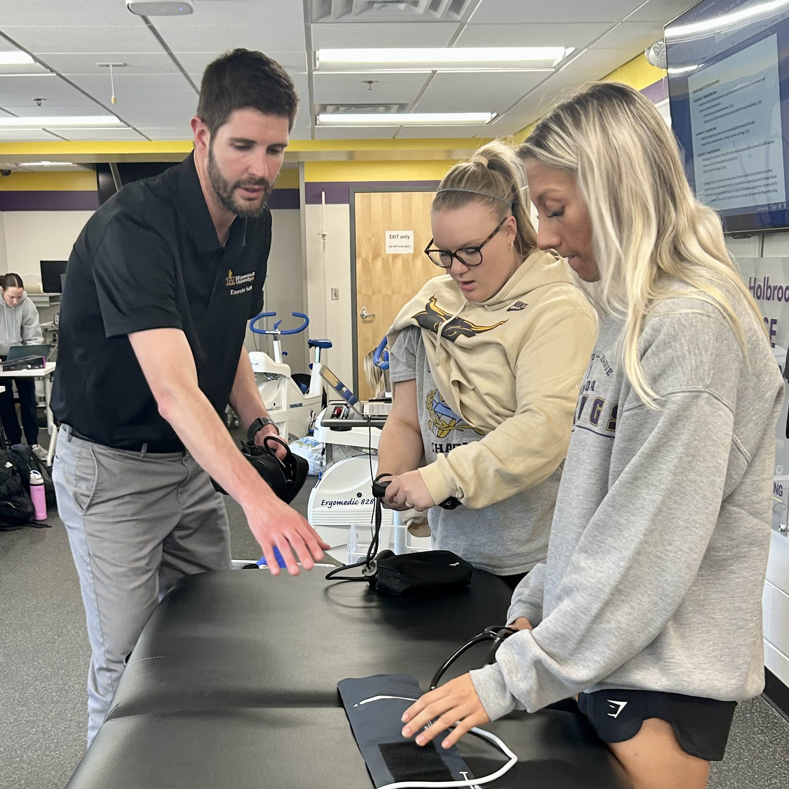 Professor working with two students on equipment in a lab. 