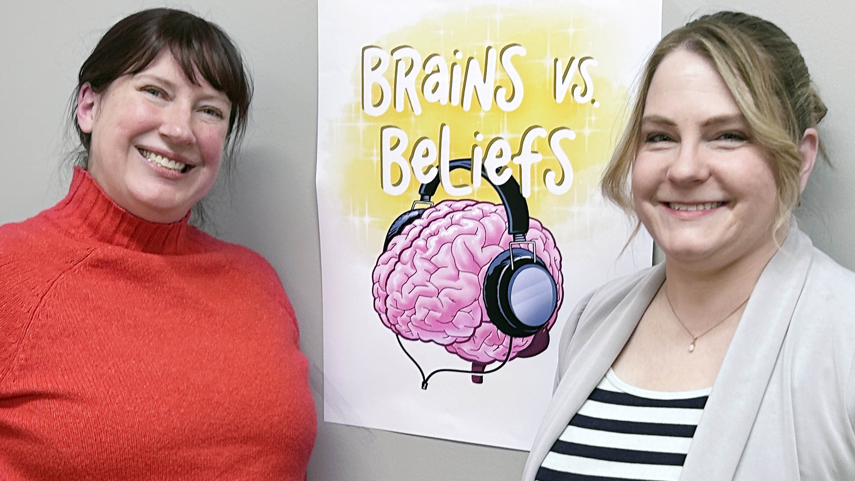 Faculty members Emily Stark and Karla Lassonde next to the Brains vs Beliefs sign 