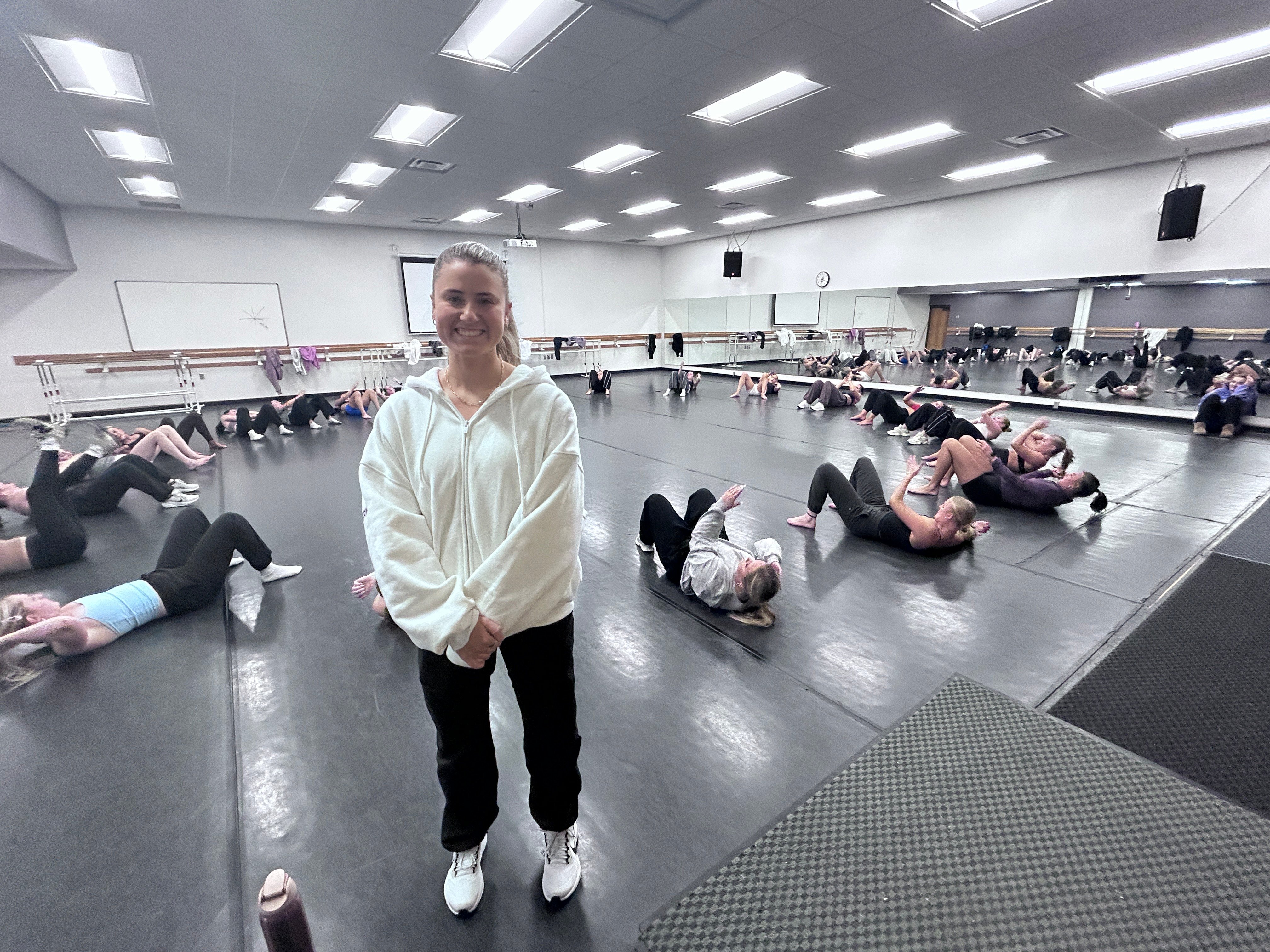 Dance Team Coach Madison Hebrink in the rehearsal studio with dancers warming up