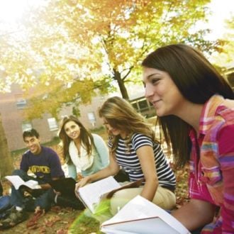 students sitting on the grass in a circle studying together