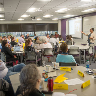 Faculty and staff sitting at tables during the concurrent enrollment research presentation