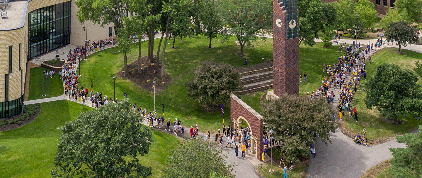 An aerial view of a group of students walking past the clock tower on campus
