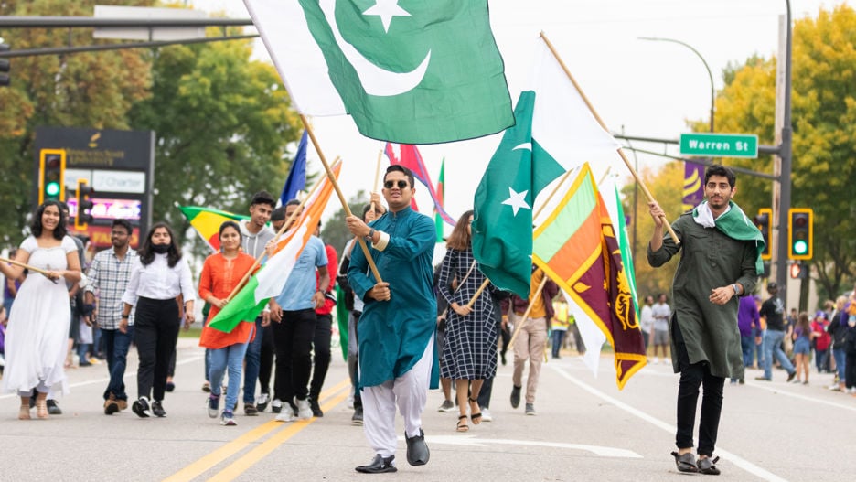Students of different nationalities showing their flag in homecoming parade