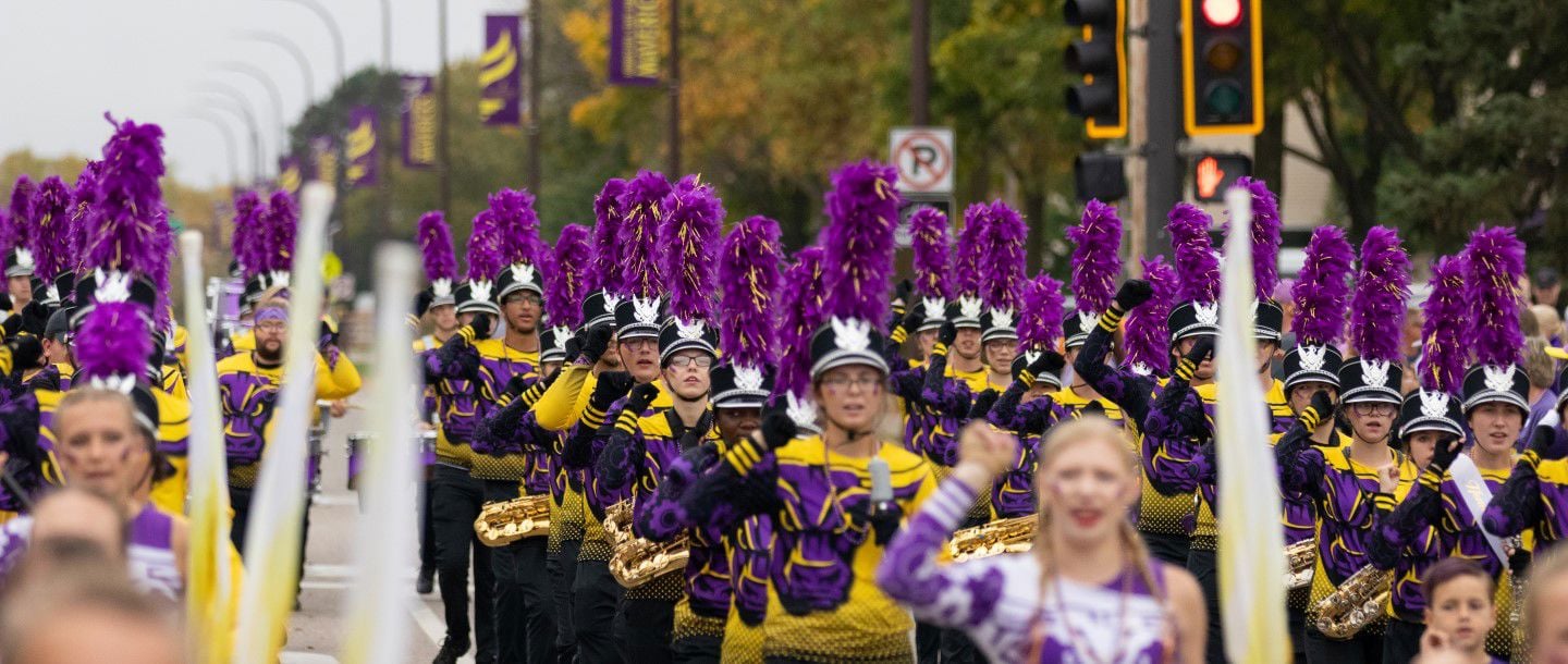 The Maverick marching band in the home coming parade dressed in purple and gold representing Minnesota State University, Mankato