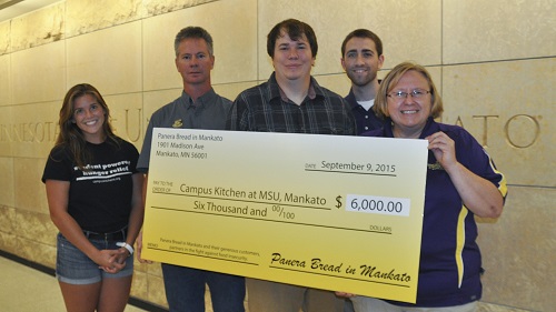 Campus Kitchen student volunteers accept a check from Panera of Mankato, to support the Campus Kitchen programs. Check says: Campus kitchen at MSU, Mankato $6,000; Six Thousand and 00/100; Panera Bread in Mankato