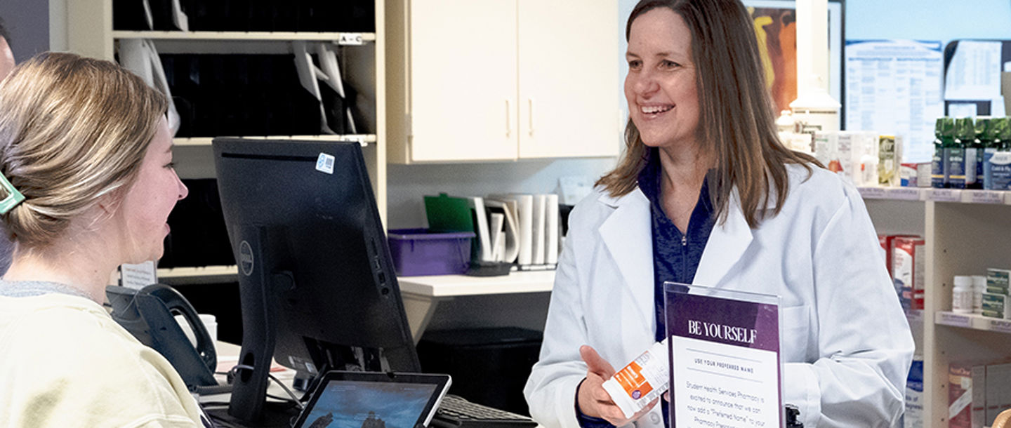 A Student Health Services pharmacist assisting a student at the counter in the pharmacy