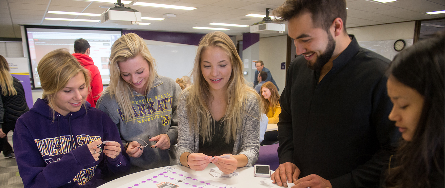 A group of students in a classroom playing a homemade board game