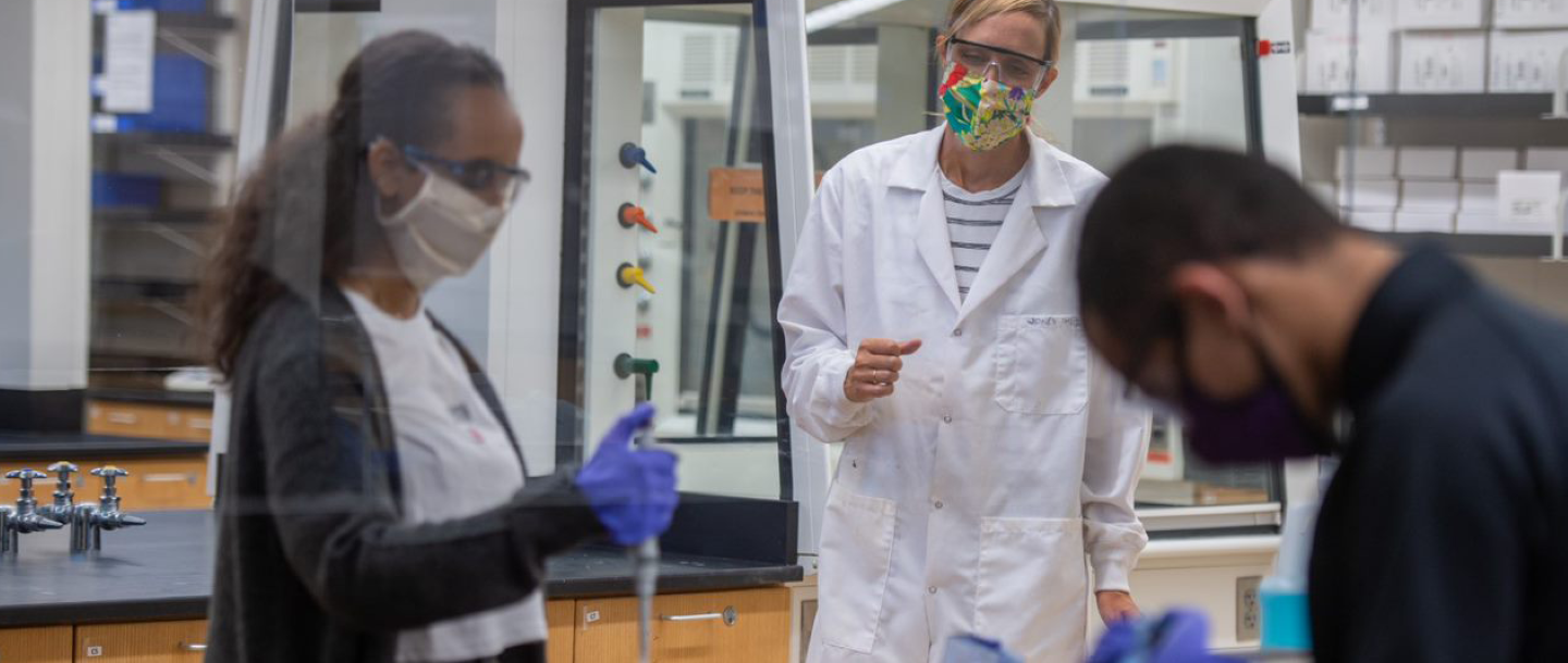 Three people wearing masks doing experiments in the lab