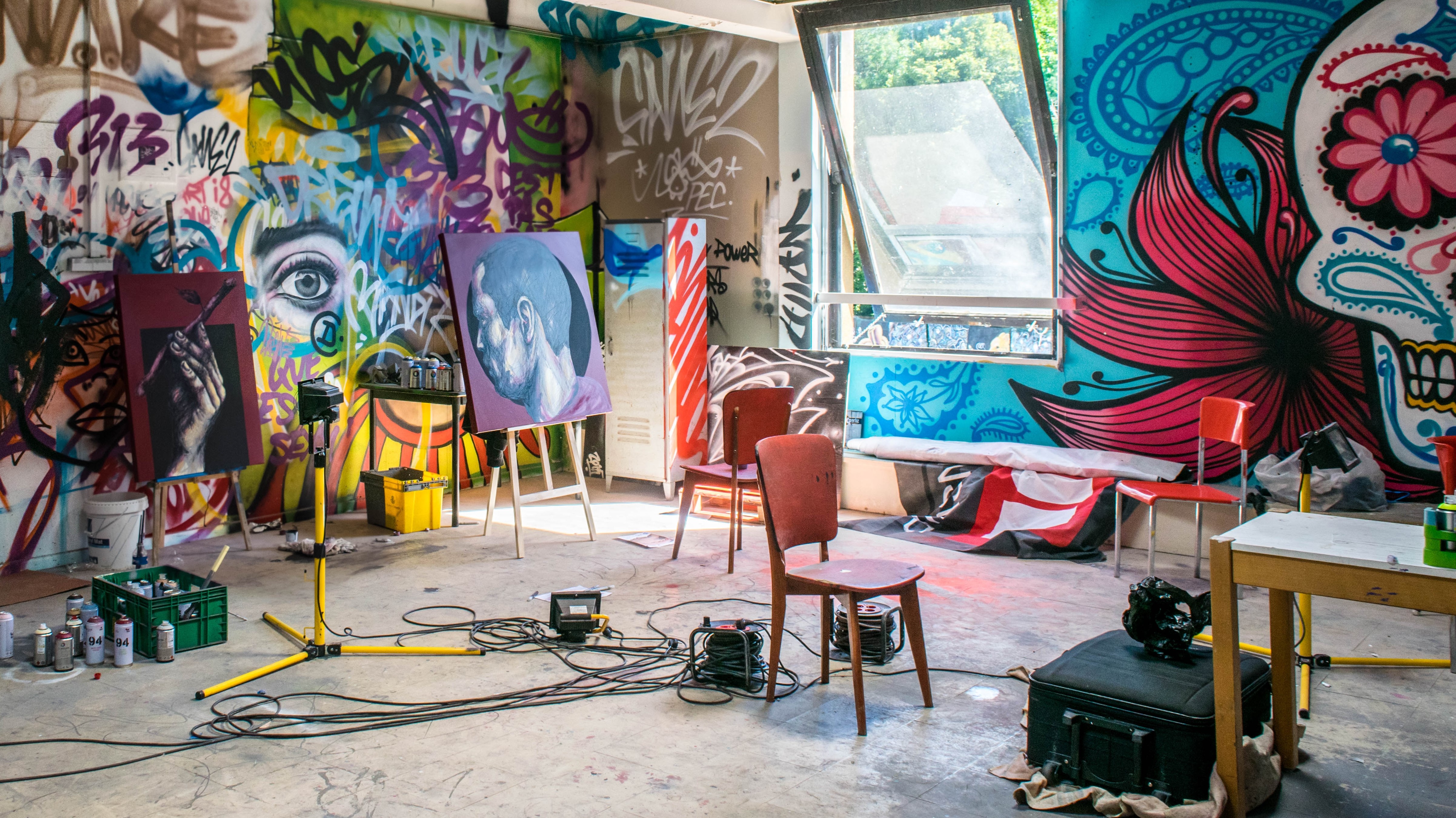 Stock photo of an art studio with paintings and audio equipment scattered around the room.