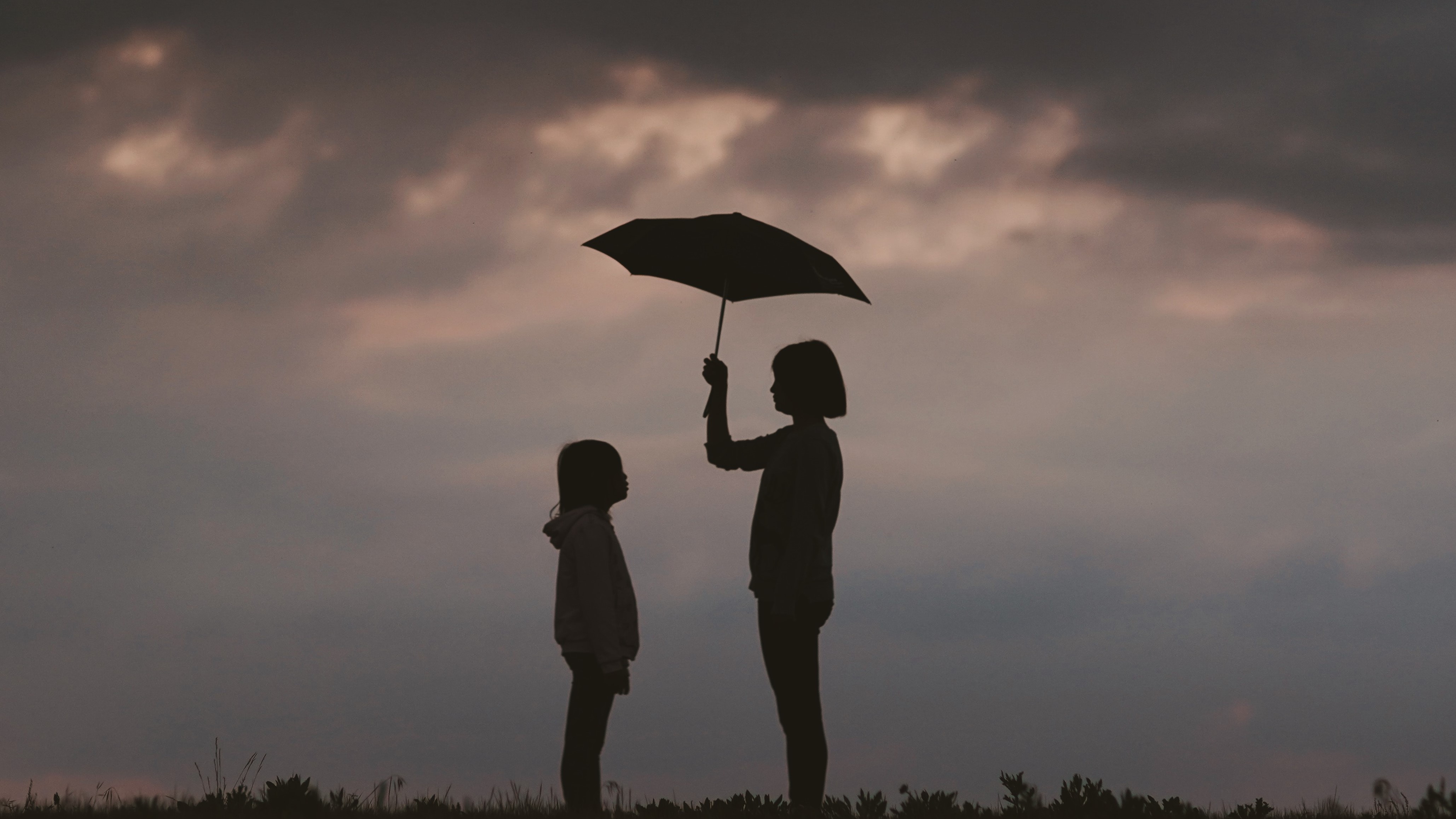 Stock photo of a silhouette of two people standing under an umbrella.