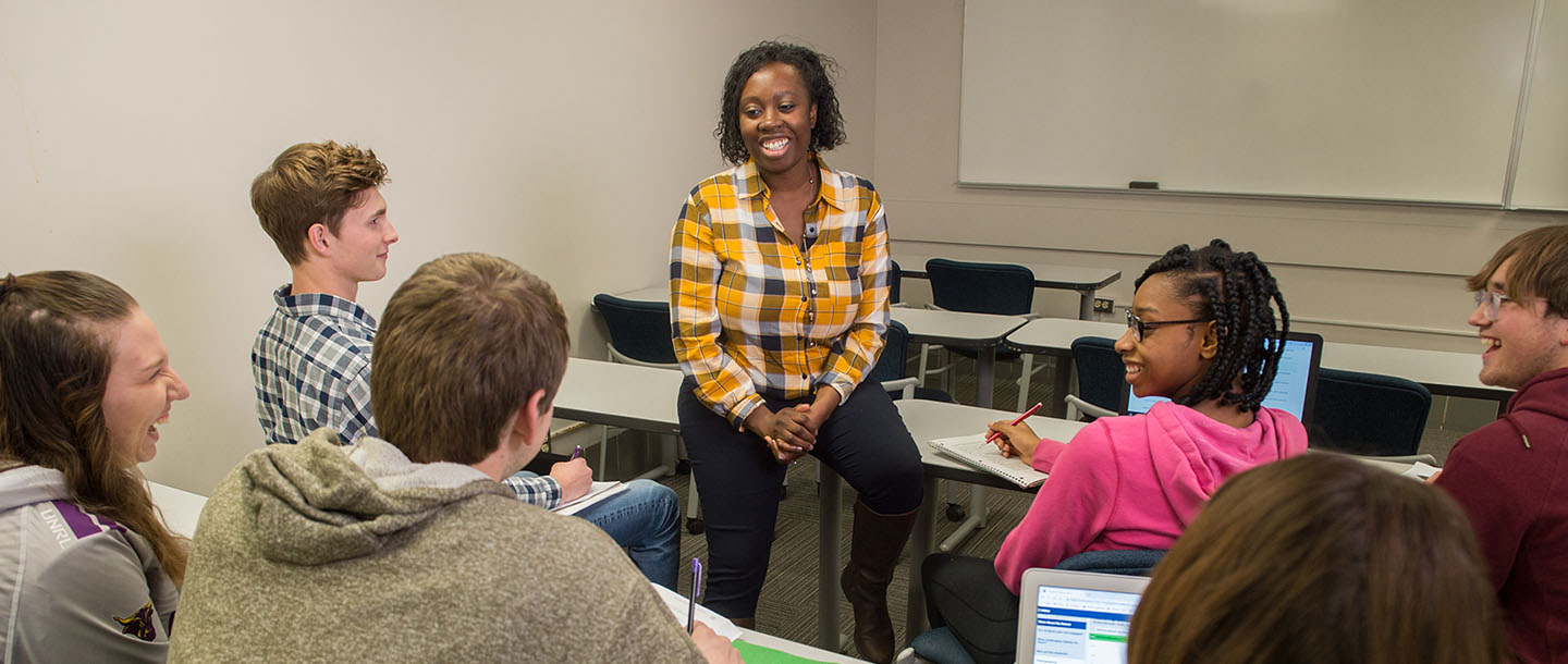 A group of students sitting in a classroom talking and smiling