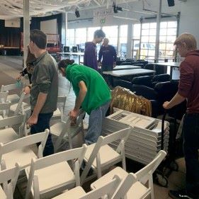 Learning Community students folding up chairs and stacking them on carts to put away during a volunteer project