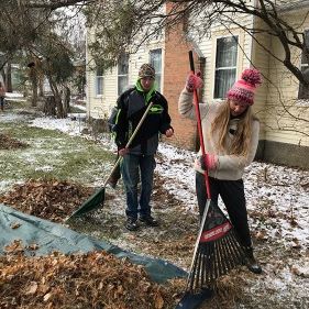 Learning Community students cleaning up a yard by racking up leaves during a volunteer project