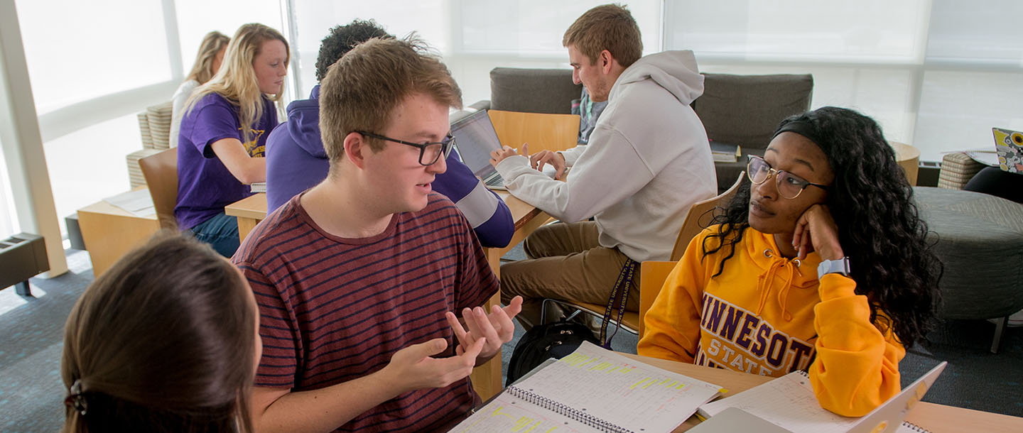 Two groups with three students in each group sitting in table and studying together