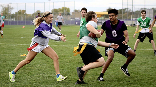 Students playing flag football on outside field