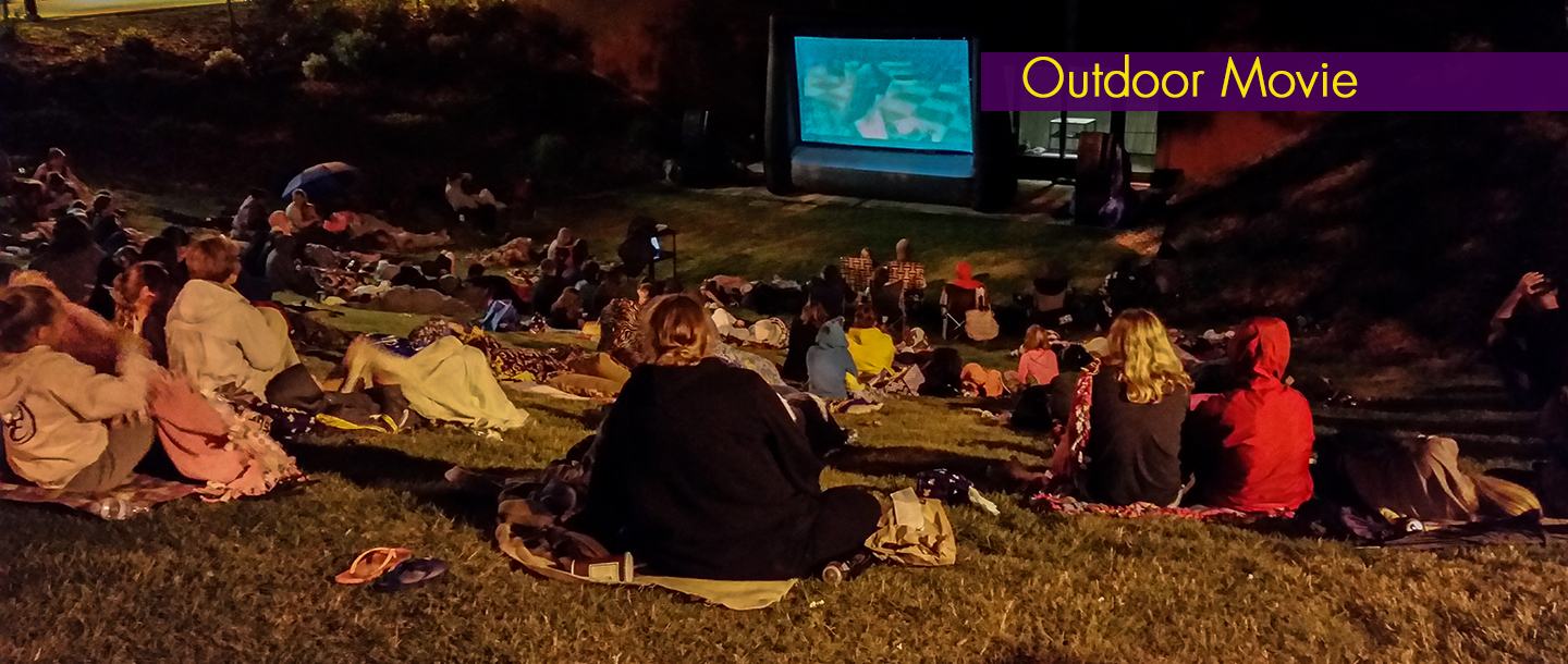 Students gathered outside on campus for the outdoor movie night event