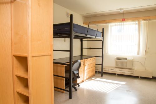 View of a renovated single room with bed and desk by window