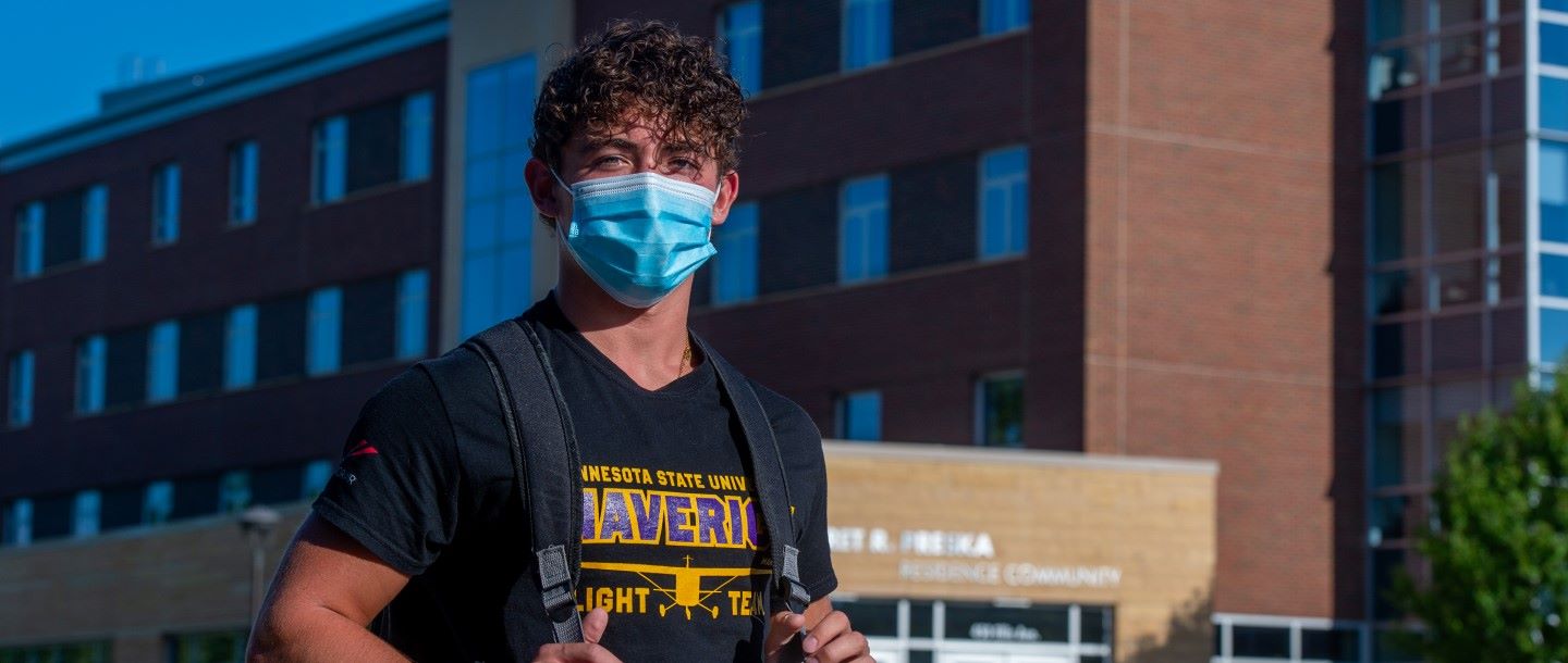 Student wearing a mask posing outside on campu