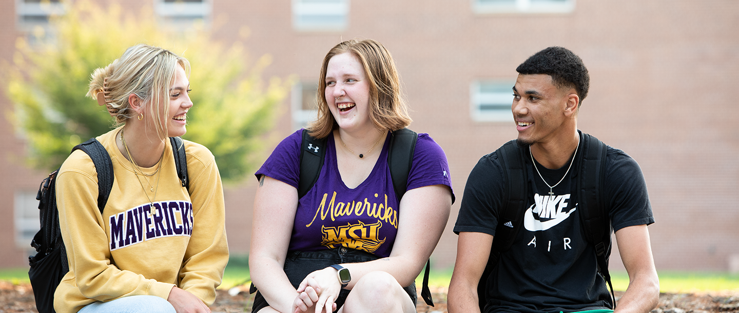 Three students sitting outside talking