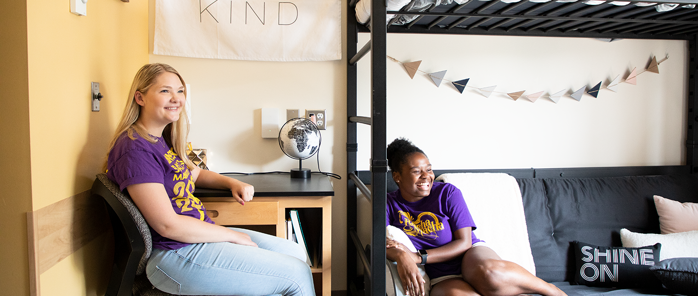Two students sitting inside the dorm laughing