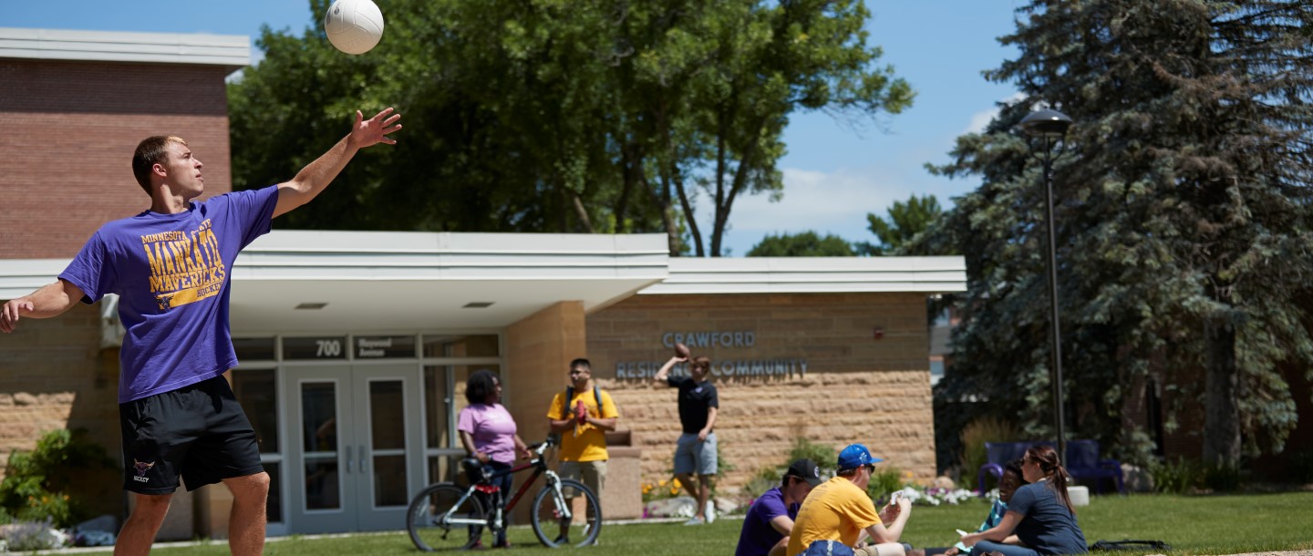 Students outside of the Crawford Residence Community building playing volleyball