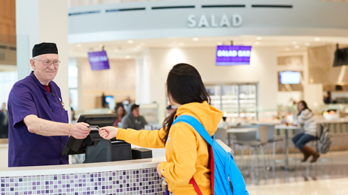 A dinning cashier taking dinning dollars from a student at the checkout counter