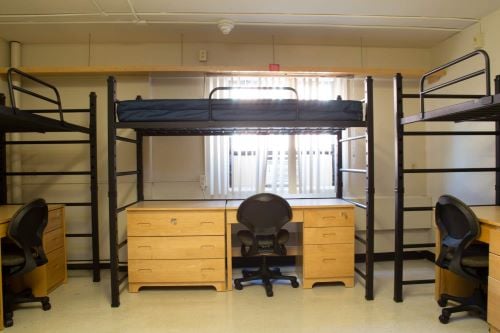 View of a basic triple room with beds and desk for three students