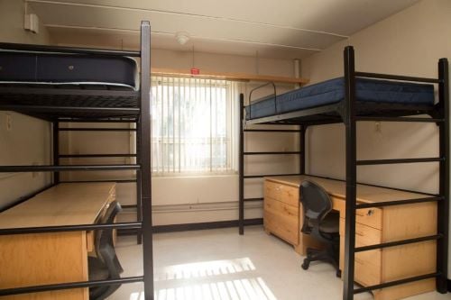 View of a basic double room with beds and desk for two students