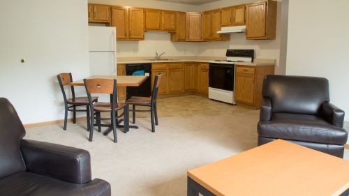 Stadium Heights five person apartment with a full kitchen, dining table and chairs, sofa, chairs and coffee table