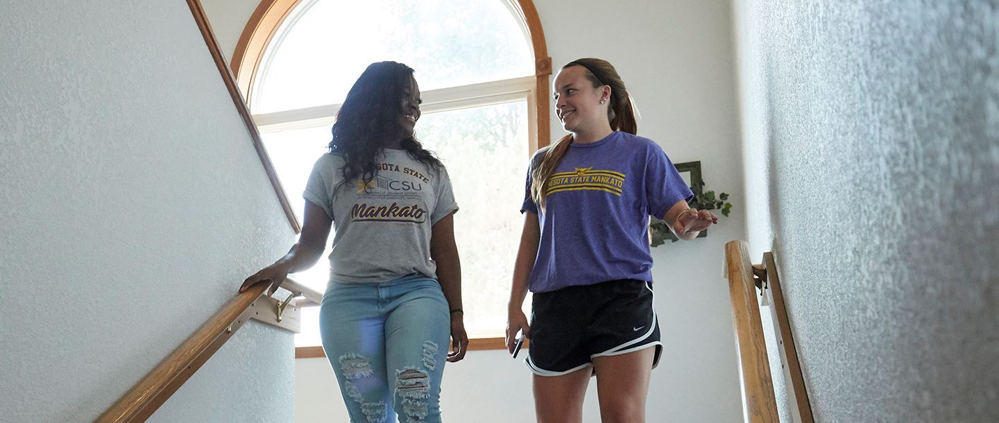 Two girls talking as they walk down the stairs