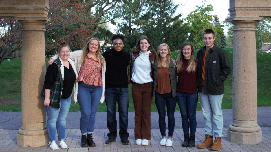 A group of students posing outside under the arch on campus