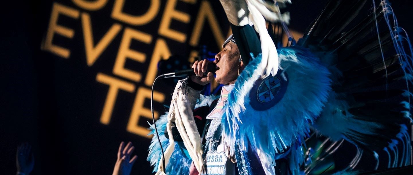 A performer in a Native American costume singing at the Superman event on campus at Minnesota State University, Mankato