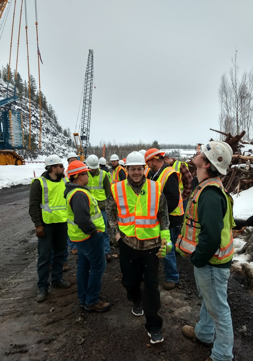 a group of men in safety vests and helmets standing on a road