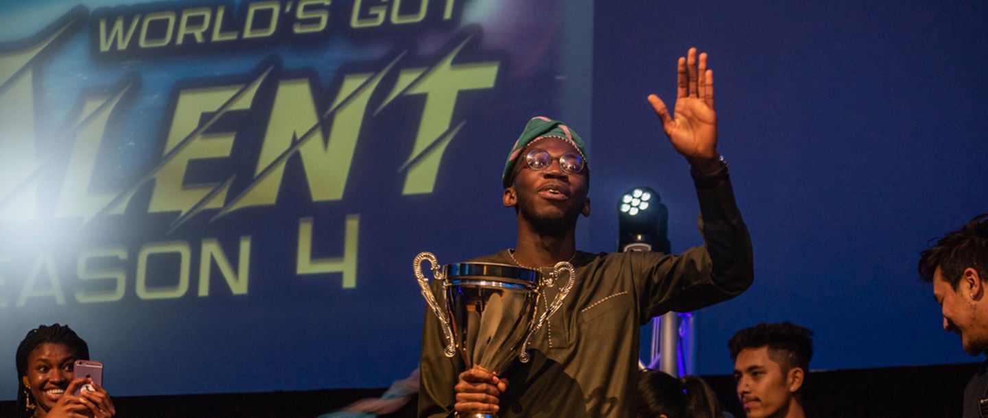 A student holding an award on stage at the World's Got Talent competition on campus