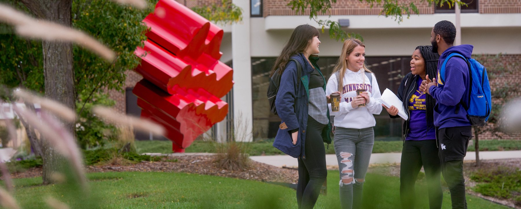 four students gathered outside on campus talking
