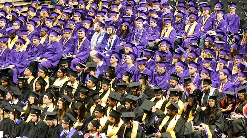aerial view of MSU student graduates in their seats at commencement. Purple robes worn by undergraduates and black robes worn my masters and doctoral graduates