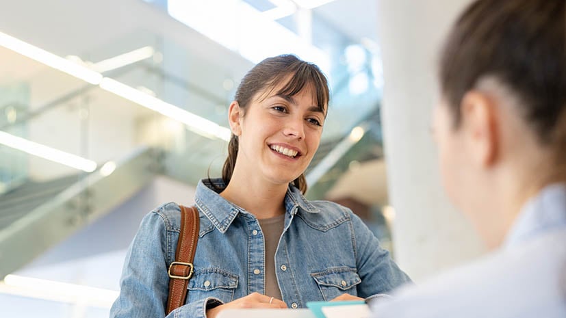 student receiving paperwork from someone sitting at a desk