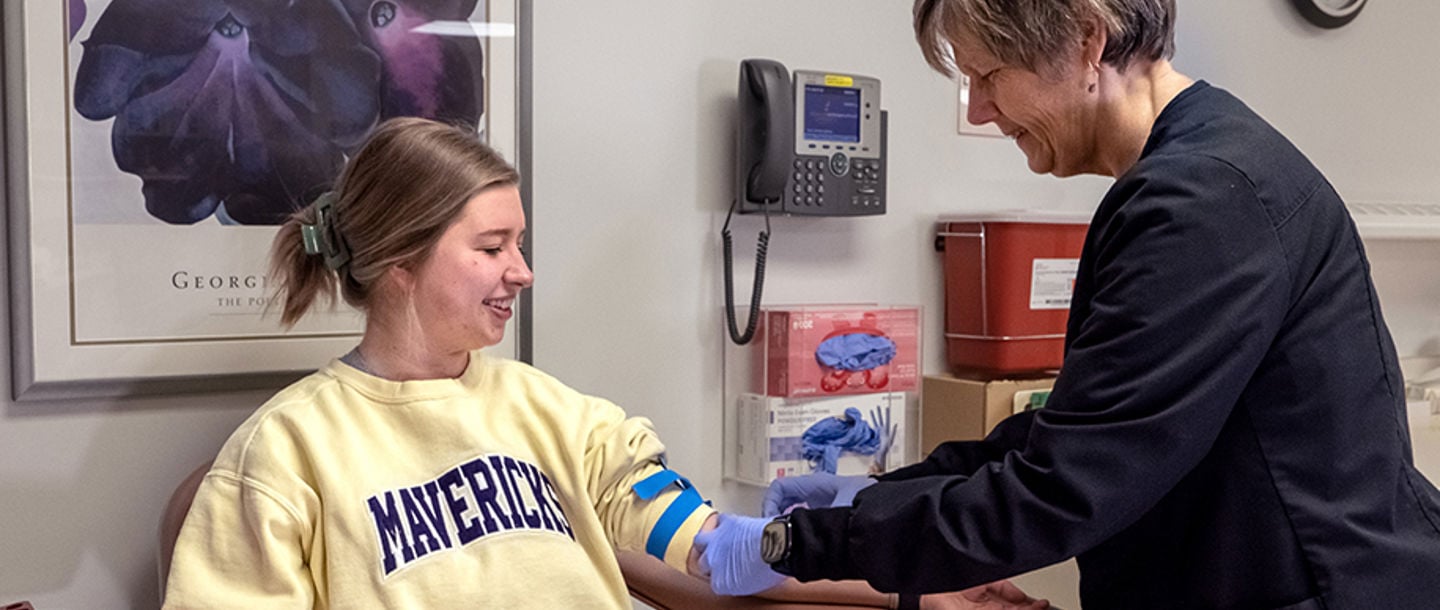 A Student Health Services nurse drawing blood from a female student patient