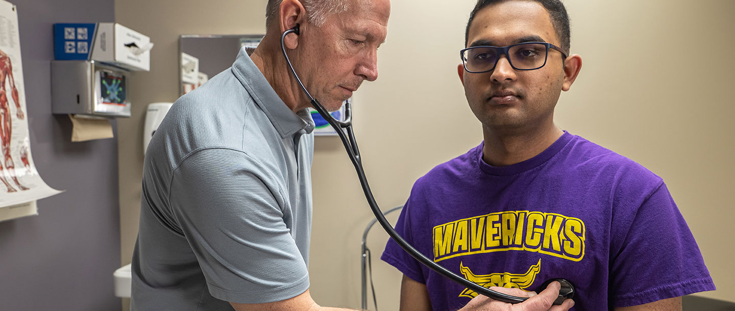 a physician using a stethoscope on a student patient